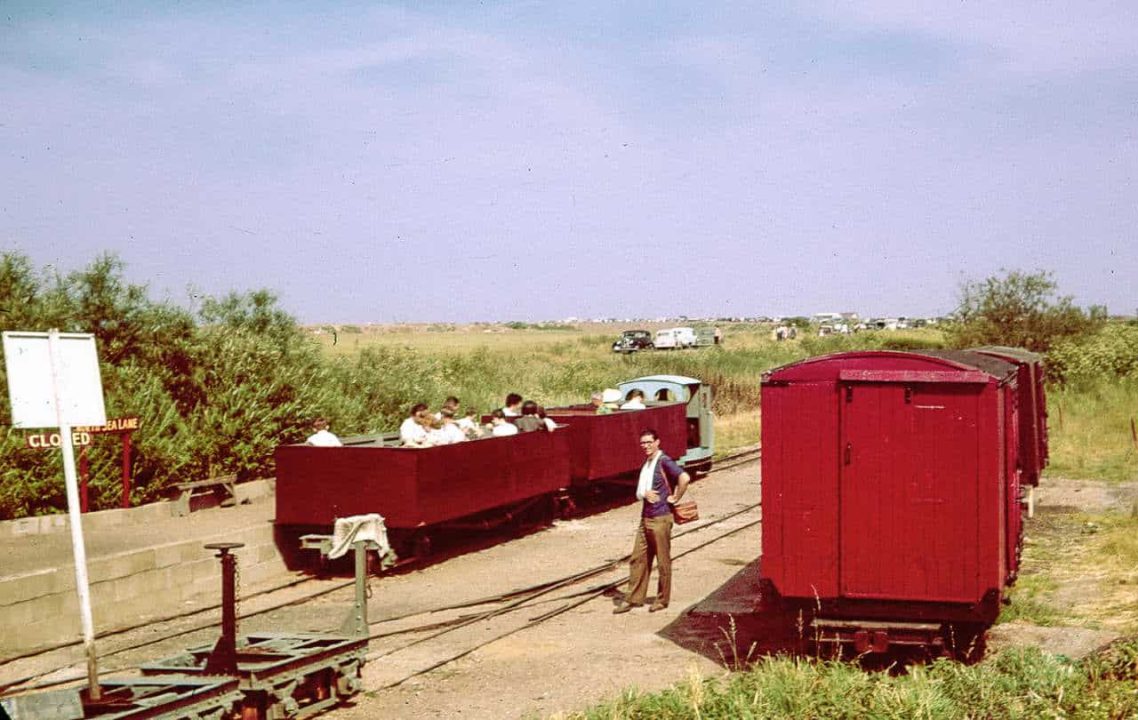 It's a sunny June day in 1961 and the LCLR has been open for less than a year but is developing rapidly. A train of two open carriages converted from First World War Class D bogie wagons is ready to depart for the Beach, behind the line's first loco, Motor Rail ‘Simplex' “Paul” (builder's number 3995 of 1926). On the right are former WW1 ambulance vans which once carried potatoes on the Nocton Estates Railway