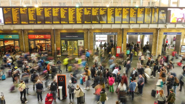 a crowed of people in a station near the display board