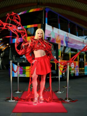 Drag Queen Bimini strikes a pose in front of a TfL PRIDE bus.