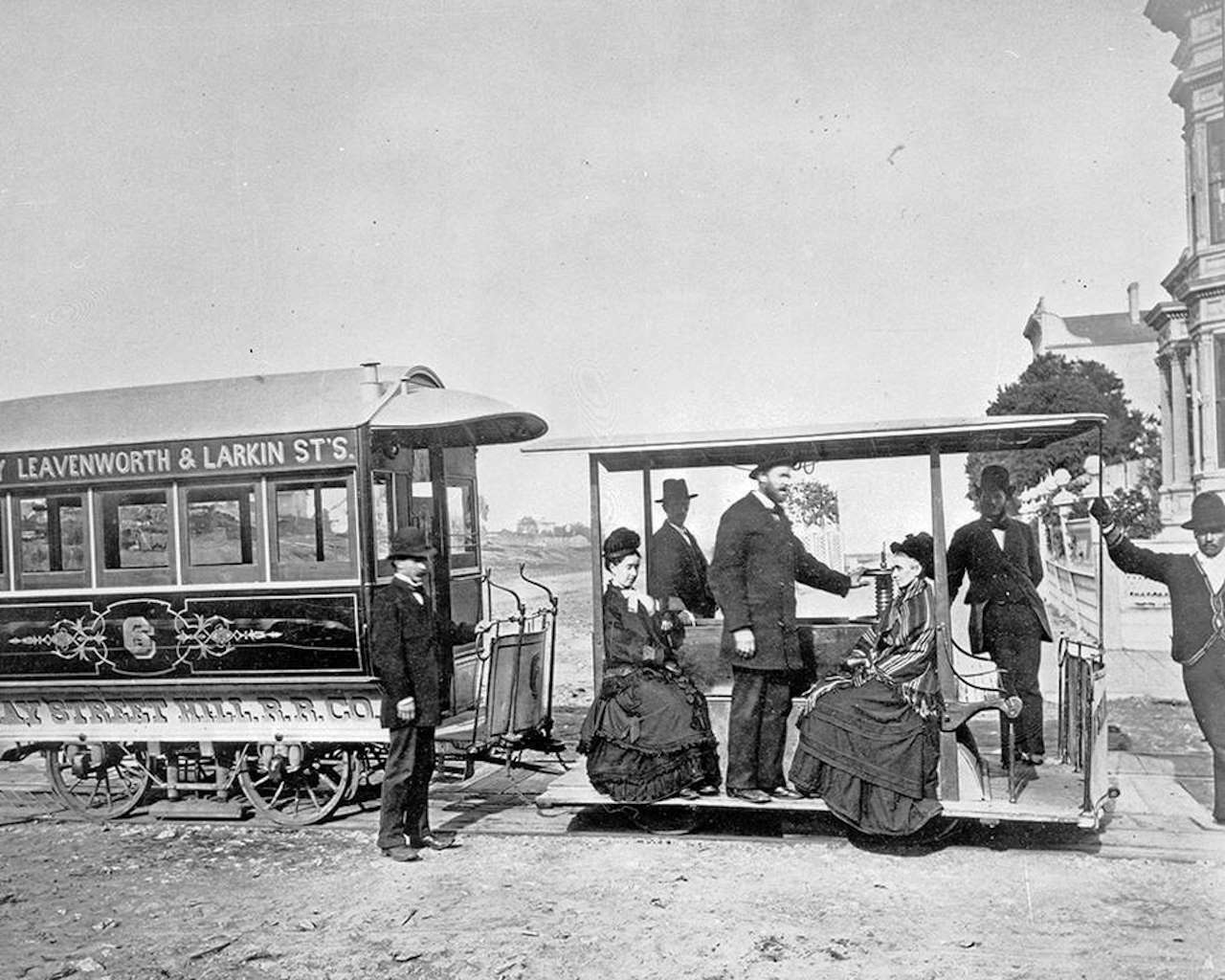 Clay Street Hill Cable Car at Clay Street and Van Ness Avenue circa October 1877. Andrew Hallidie stands on the open-air cable car between two seated women