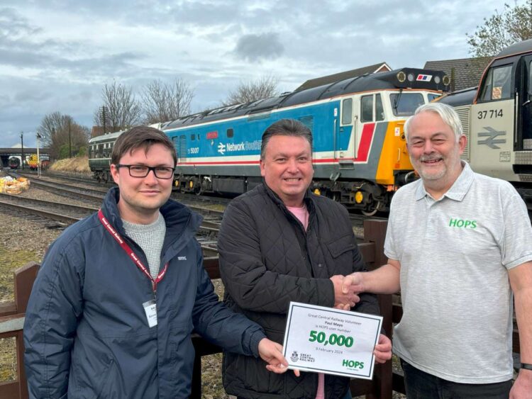 Paul Mayo shakes hands with Bob Machon of HOPs as he receives his HOPs member no. 50,000 certificate in the presence of Great Central Railway Director Scott Manley at Loughborough Central station