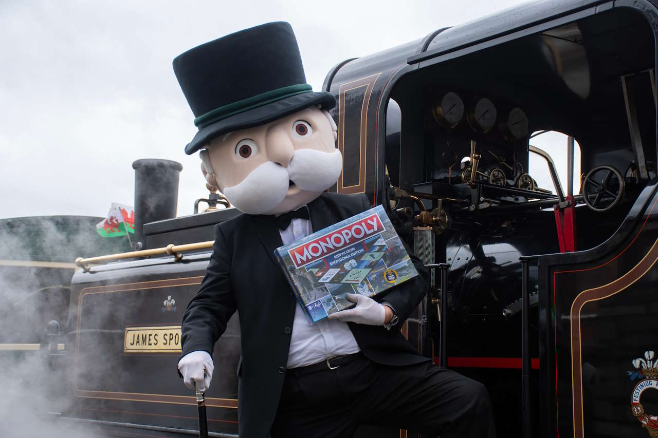 Mr Monopoly and the new MONOPOLY: Eryri / Snowdonia Edition, alongside Double Fairlie engine, James Spooner, at Porthmadog Harbour Station.