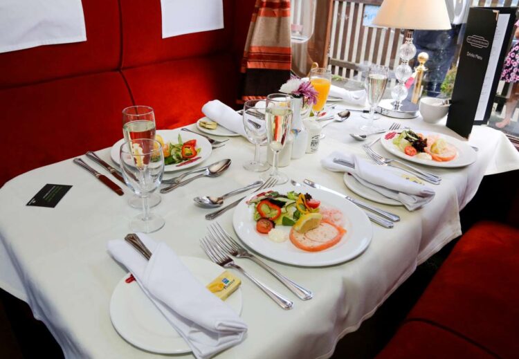 Main course and drinks displayed on a dining table on an ELR train.
