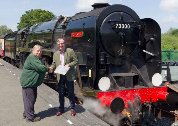 Charlie Masterson (left) thanks Richard Broyd CBE and presents him with a certificate next to ‘Britannia' on Robertsbridge Station. // Credit: Alan Crotty