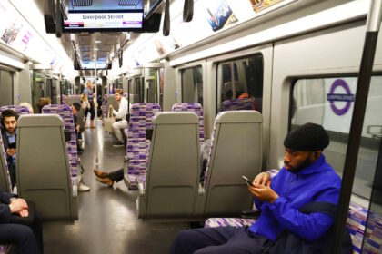 Customer using mobile phone on the Elizabeth line. // Credit: Transport for London