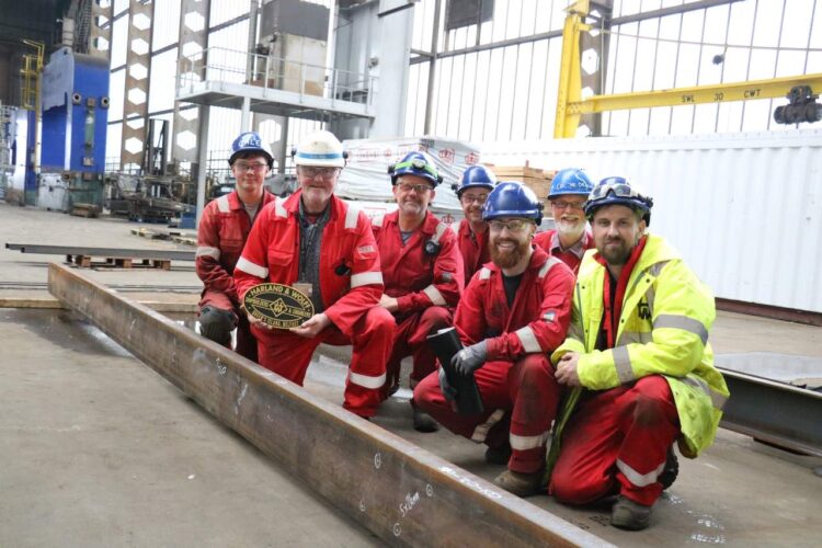 Brian Welsh, H&W Operations Manager with his team of apprentices (with the DCDR's David Crone, underframe designer, at the back) with the marked out steel for the new underframe - Downpatrick and County Down Railway