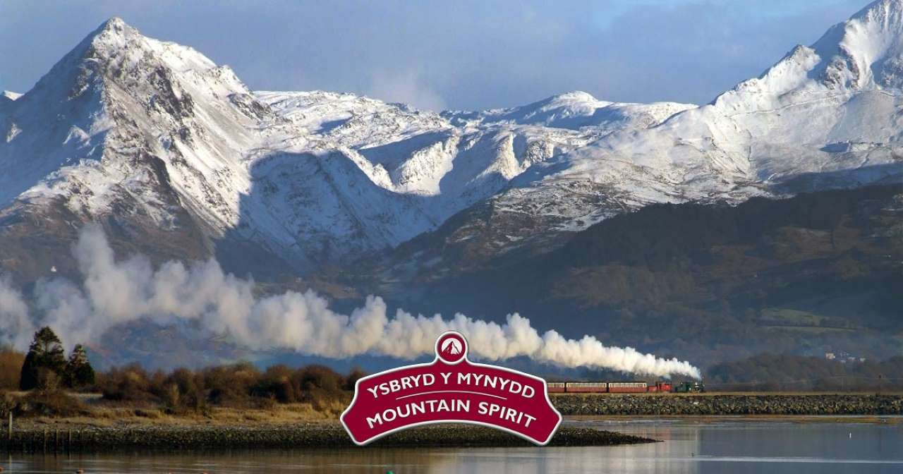 The Christmas Mountain Spirit train against an impressive mountain backdrop.