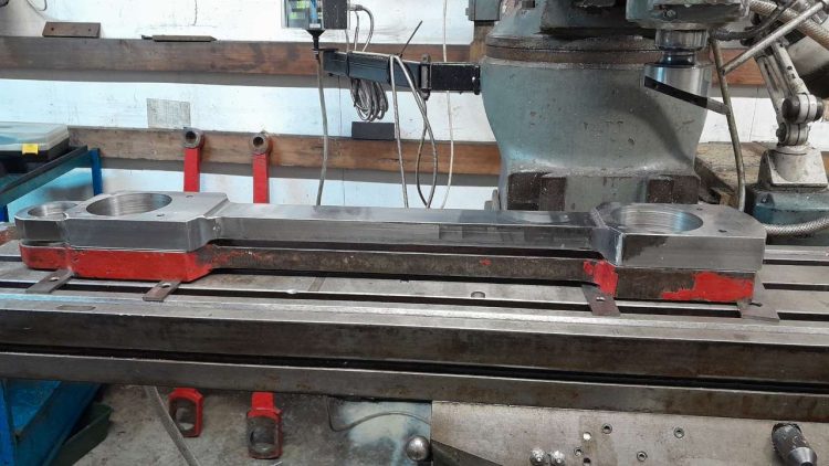 One of Beddgelert's new connecting rods sitting above an old one on a milling machine - Fairbourne Railway